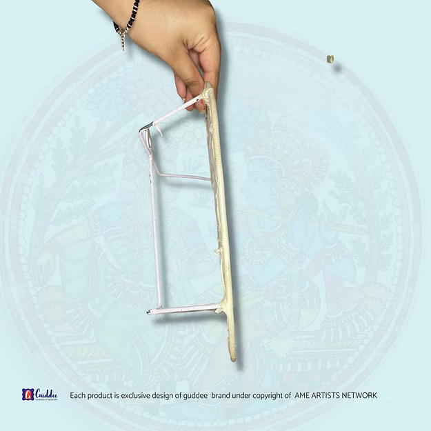 Hand holding a traditional tool against a light blue background with circular patterns
