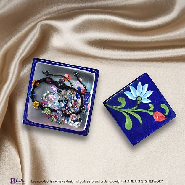 A handcrafted mini lotus blue pottery box opened on a vanity table to show rings and small jewelry stored safely inside.