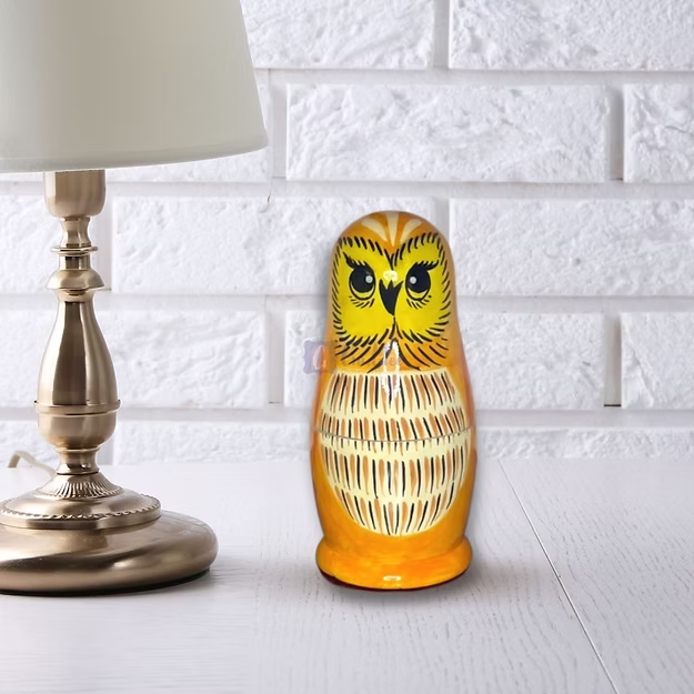 Close-up of the natural pine wood grain and glossy hand-painted owl face detailing on Guddee's stacking doll shell.