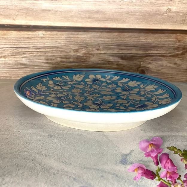 A premium handcrafted ceramic blue pottery platter styled as a luxury fruit display bowl on a modern wooden dining table.