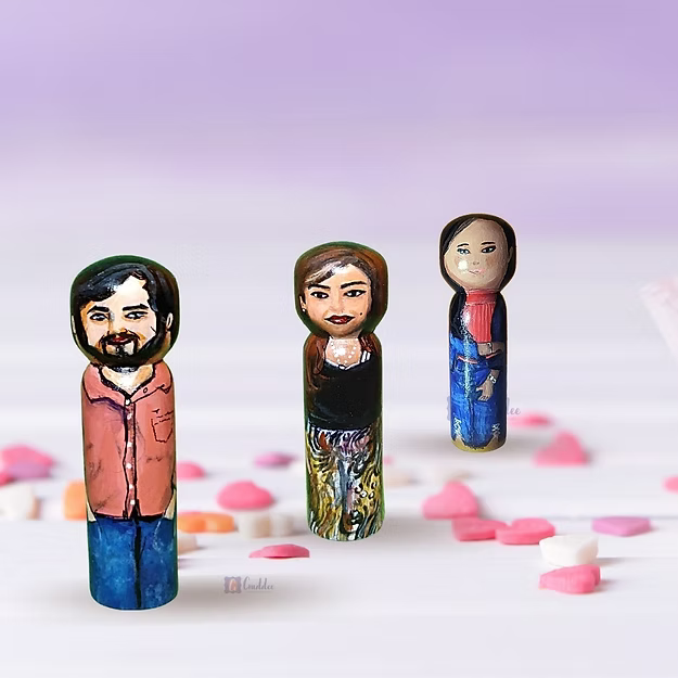Three custom wooden peg dolls of varying heights hand-painted by regional artisans to match a 3-member family portrait.