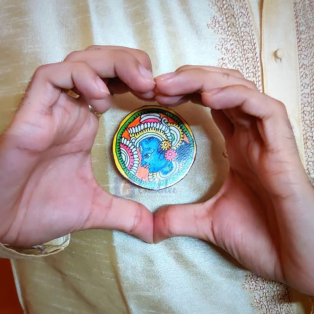 A man wearing the handcrafted Krishna synthetic leather rakhi styled as a divine lapel brooch on festive ethnic wear.
