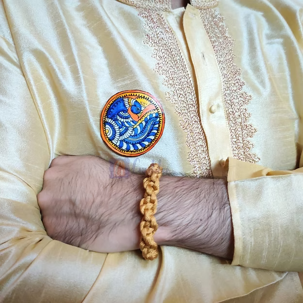A man wearing the handcrafted peacock synthetic leather rakhi converted as an elegant lapel brooch on a festive ethnic outfit.