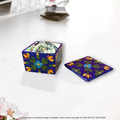 A handcrafted mini floral blossom blue pottery box opened on a vanity table to show rings and small jewelry stored safely inside.