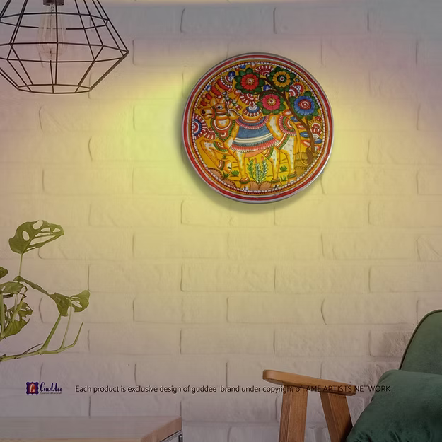 A lit translucent Tholu Bommalata leather Nandi sconce projecting a glowing, multi-colored folk pattern on a hallway wall.