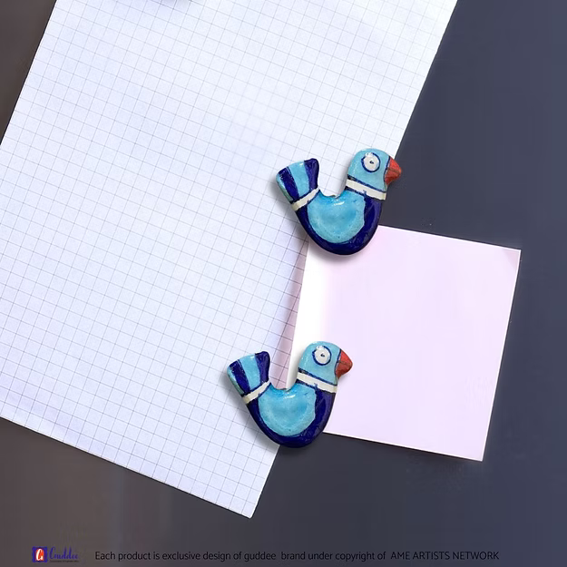 A handcrafted traditional blue bird couple magnet holding a memo securely on a kitchen refrigerator door.
