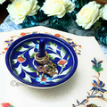 Gold engagement rings and jewelry stored elegantly inside a dark blue handcrafted ceramic blue pottery trinket dish.