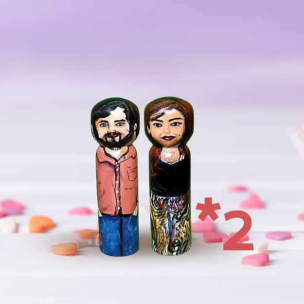 Two peg dolls of a man and woman with a heart-shaped number '2' on a light purple background.