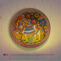 A lit translucent Tholu Bommalata leather Nandi sconce projecting a glowing, multi-colored folk pattern on a hallway wall.