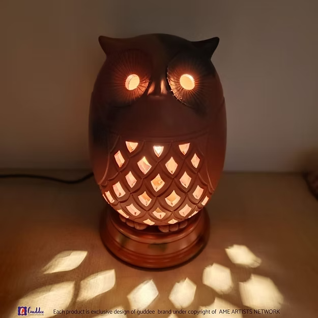 An lit illuminated handcrafted terracotta owl night lamp casting warm ambient patterns on a bedroom side table.