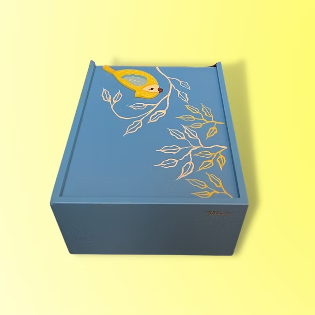 Close-up of the smooth mechanical slider track grooves and vibrant paint pigments on Guddee's bird artisan storage chest.