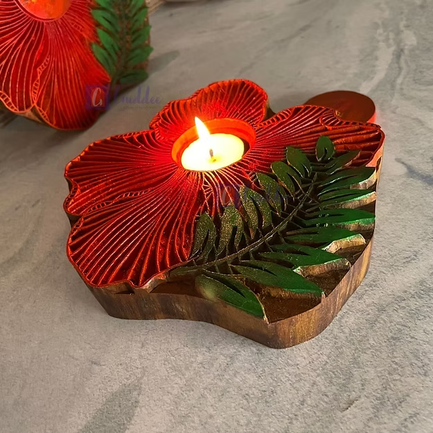 A lit rosewood hibiscus tea light holder sitting as a warm decorative centerpiece table runner accent on a wooden dining table.