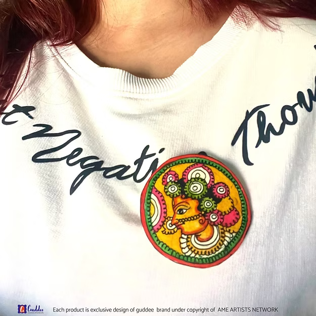 A handcrafted Tholu Bommalata Radha leather brooch pinned elegantly as a wearable art fashion statement on clothing.
