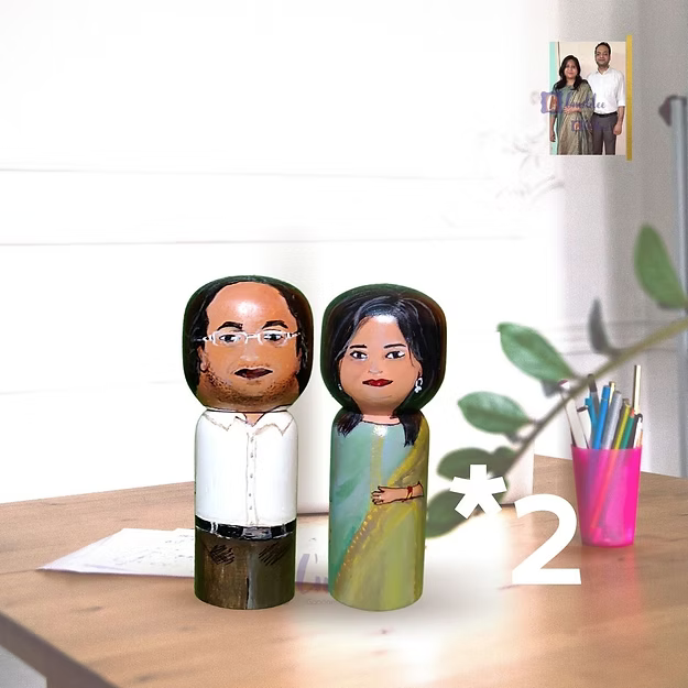 Two peg dolls of a man and woman with a heart-shaped number '2' on a light purple background.