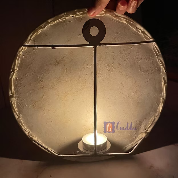 Hand holding a back side of the Circle Nandi faux leather Tholu Bommalata wall decor against a light blue background with circular patterns