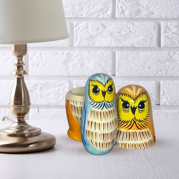 Close-up of the natural pine wood grain and glossy hand-painted owl face detailing on Guddee's stacking doll shell.