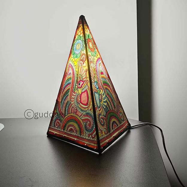 A lit triangular synthetic leather peacock silhouette lamp casting a warm ambient glow as a decorative table centerpiece.