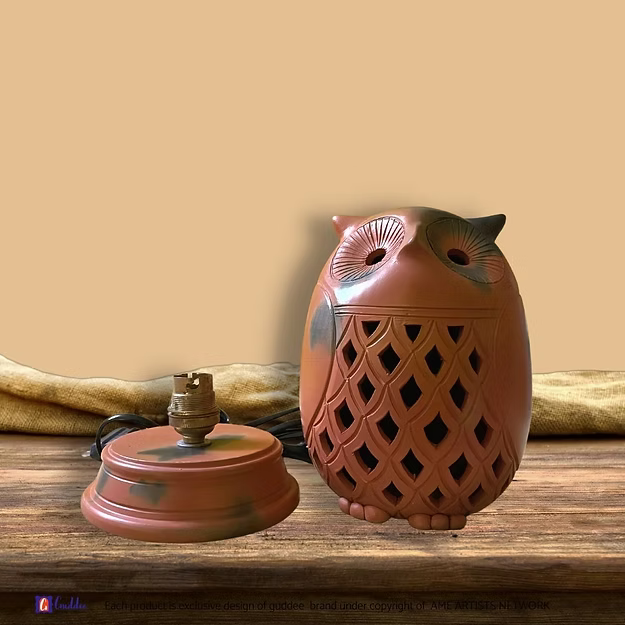 An illuminated handcrafted terracotta owl night lamp casting warm ambient patterns on a bedroom side table.