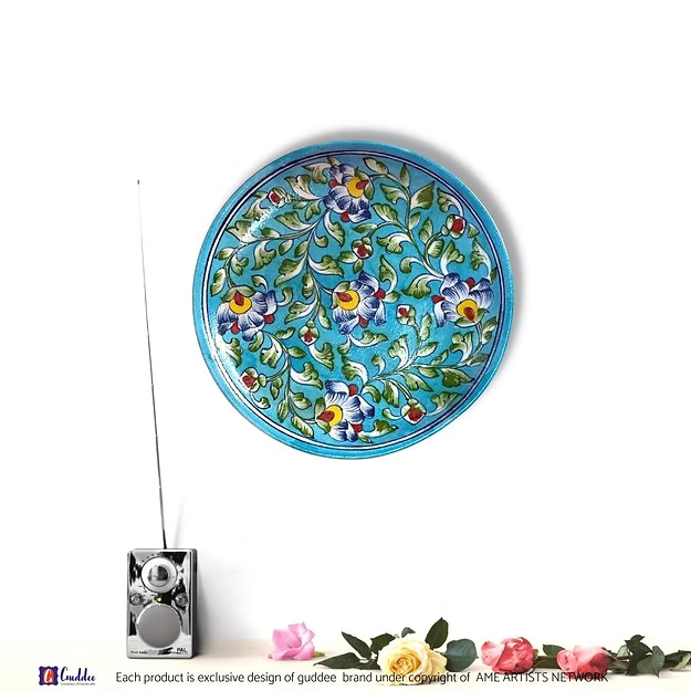 A handcrafted 10-inch floral hues blue pottery wall plate hanging as an elegant focal point in a modern living room.