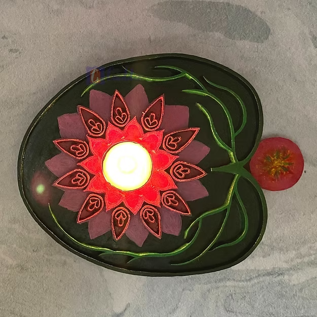 A lit rosewood lotus tealight holder sitting as a warm decorative centerpiece table runner accent on a wooden dining table.